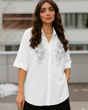 Woman wearing a white blouse with floral embroidery outdoors