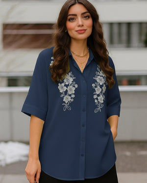 Woman wearing a blue shirt with floral embroidery outdoors
