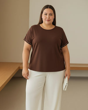 Woman wearing a brown top with white pants in a minimal indoor setting
