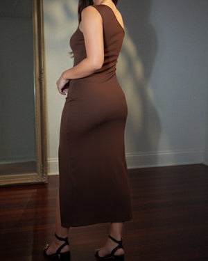 Person wearing a brown dress standing in front of a mirror.