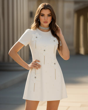 Woman wearing a white dress with floral details in an outdoor setting