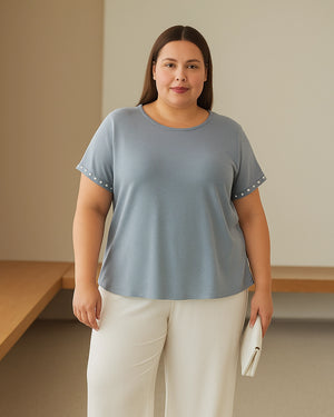 Woman wearing a light blue t-shirt and white pants indoors.