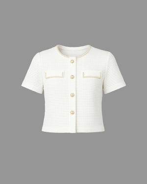 White short-sleeve jacket with gold buttons and trim on a gray background