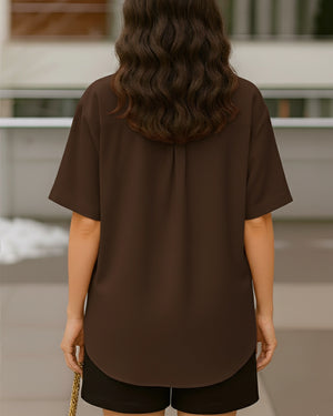 Person wearing a brown shirt and black shorts standing outdoors.