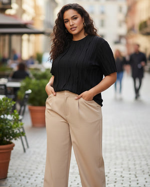Woman wearing a black top and beige pants standing on a street.