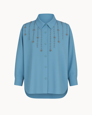 Blue shirt with decorative embellishments on a white background