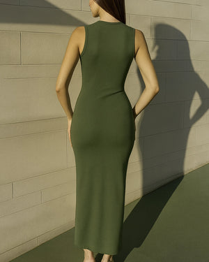Woman wearing a green dress standing against a beige wall.