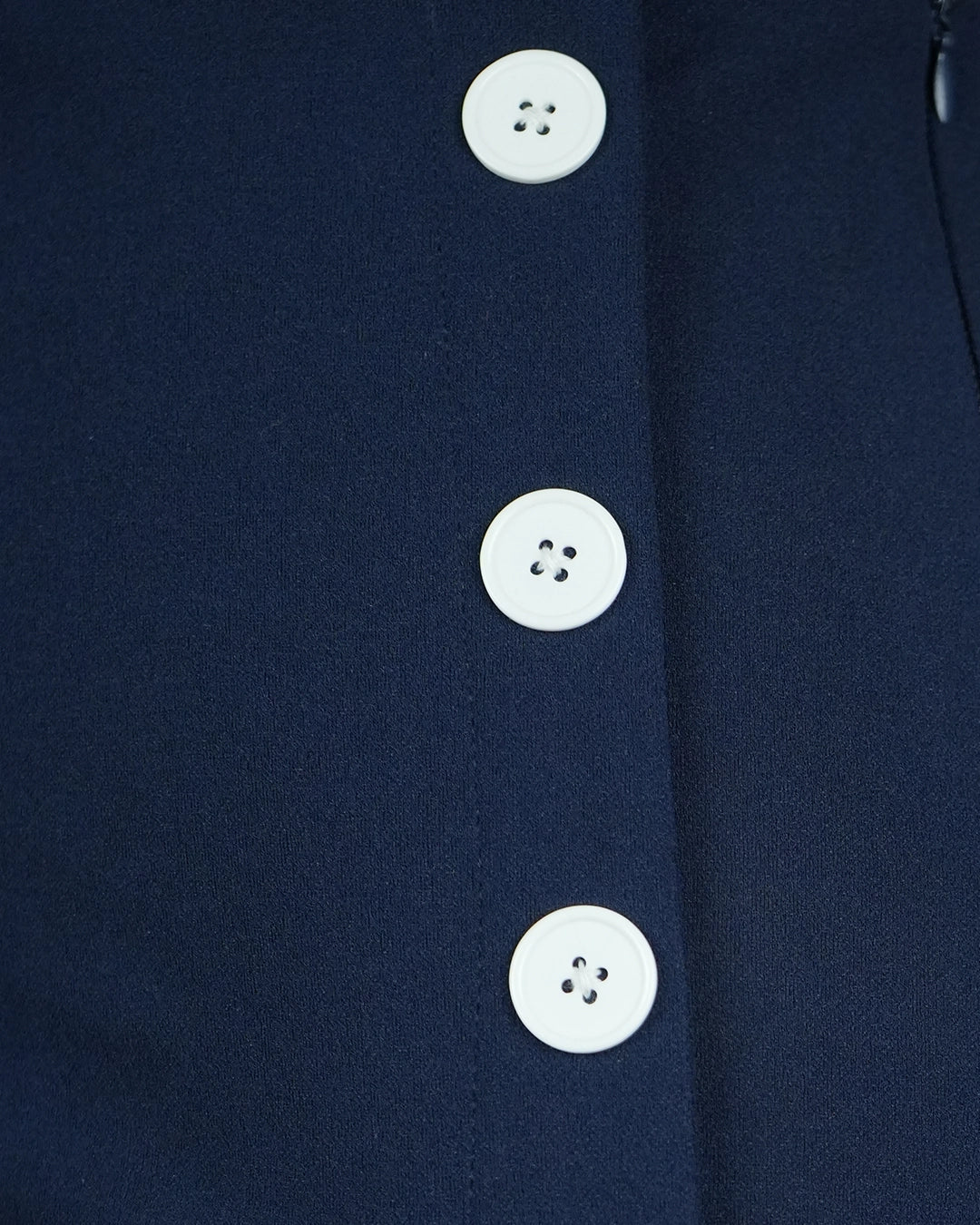 Close-up of a navy blue garment with white buttons