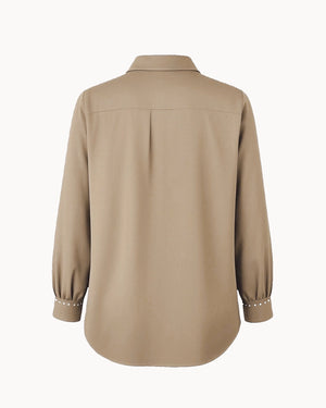 Beige shirt with pearl embellishments on cuffs and collar against a white background