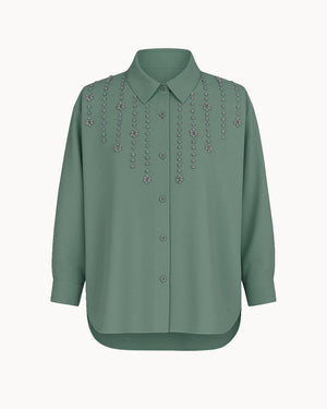 Green blouse with decorative embellishments on a white background