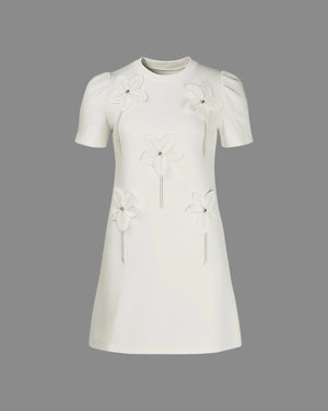 White dress with floral embellishments on a gray background