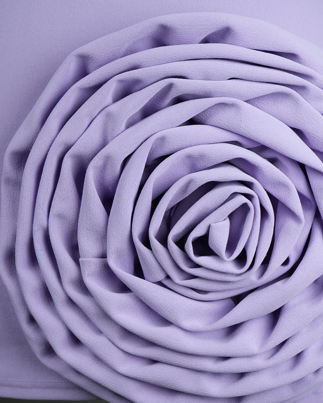 Close-up of a purple fabric flower on a matching purple background