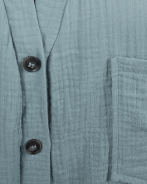 Close-up of a textured blue garment with buttons and a pocket.
