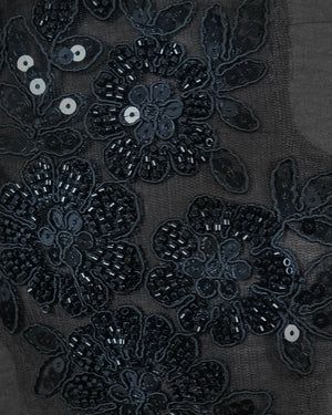 Close-up of black floral embroidery on a dark fabric background
