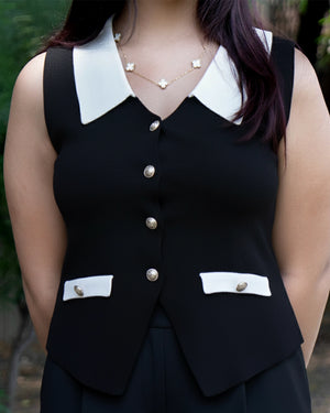 Black vest with white collar and buttons worn by a person, blurred background