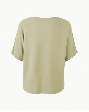 Light green blouse with lace trim on sleeves and hem against a white background