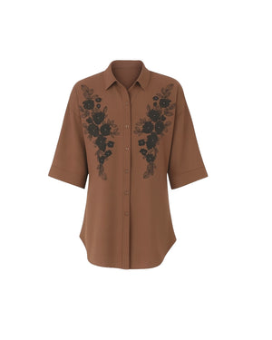 Brown shirt with black floral embroidery on a white background