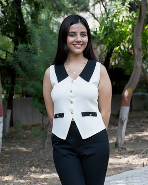 Woman wearing a white sleeveless vest with black accents outdoors