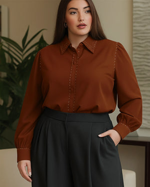Woman wearing a brown blouse with intricate detailing in a room with plants and decor.