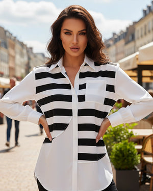 Woman wearing a black and white striped shirt outdoors with buildings and greenery in the background