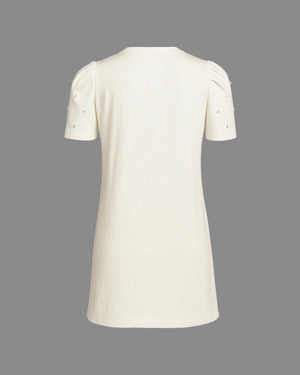 White dress with short sleeves and pearl embellishments on a gray background