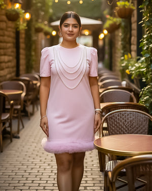 Woman in a pink dress standing in an outdoor cafe setting