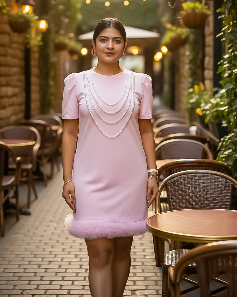 Woman in a pink dress standing in an outdoor cafe setting