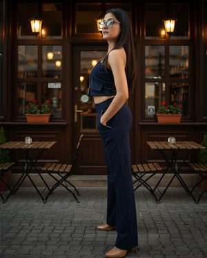 Woman in a navy outfit standing in front of a café with outdoor seating.