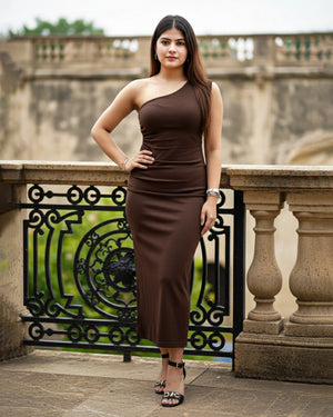 Woman in a brown dress standing on a balcony with decorative railings.