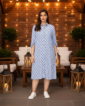 Woman wearing a light blue dress with dark polka dots in an outdoor setting with string lights and lanterns.