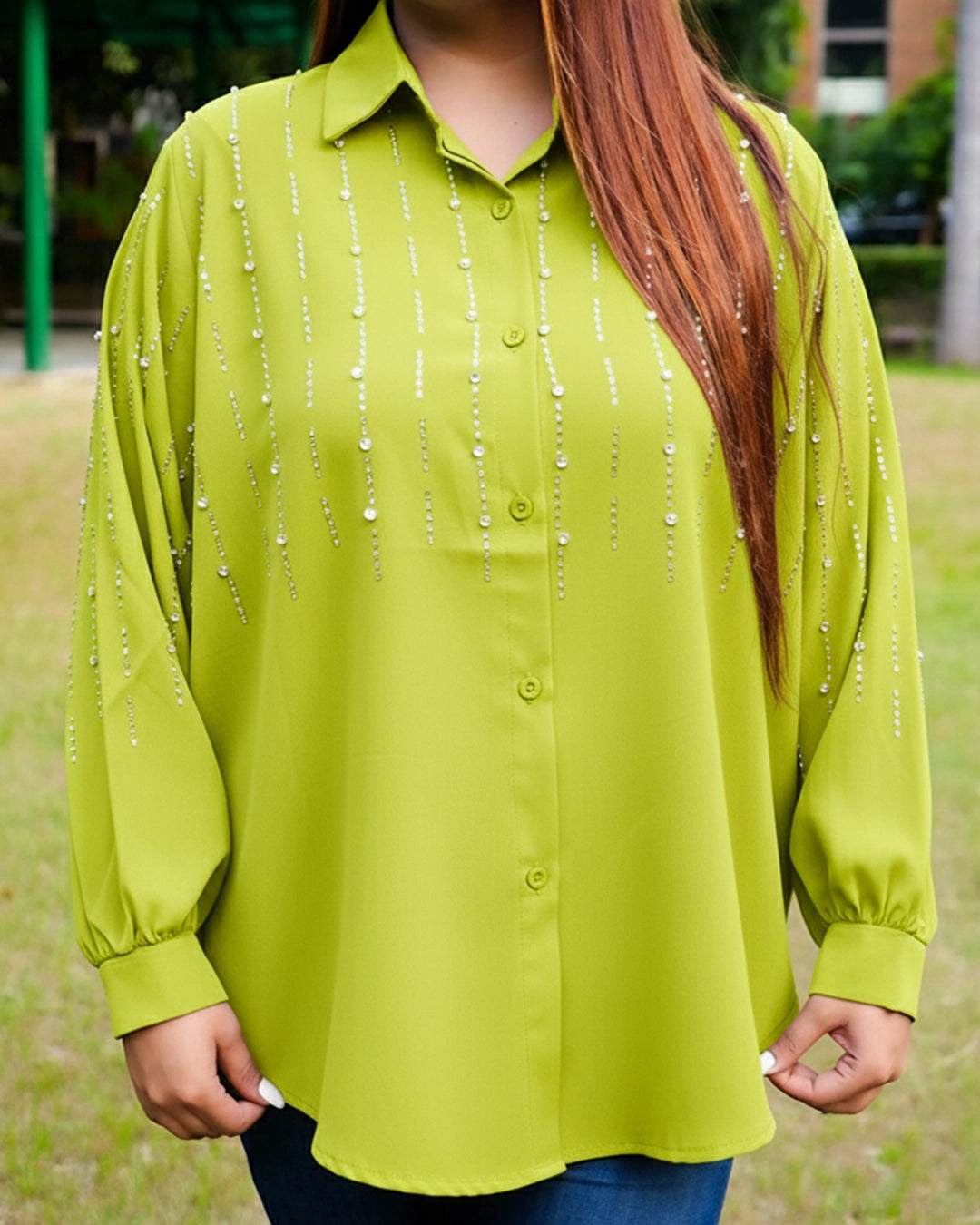 Person wearing a green blouse with bead details outdoors