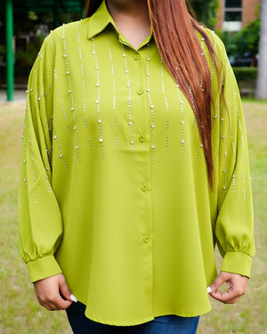 Person wearing a green blouse with bead details outdoors