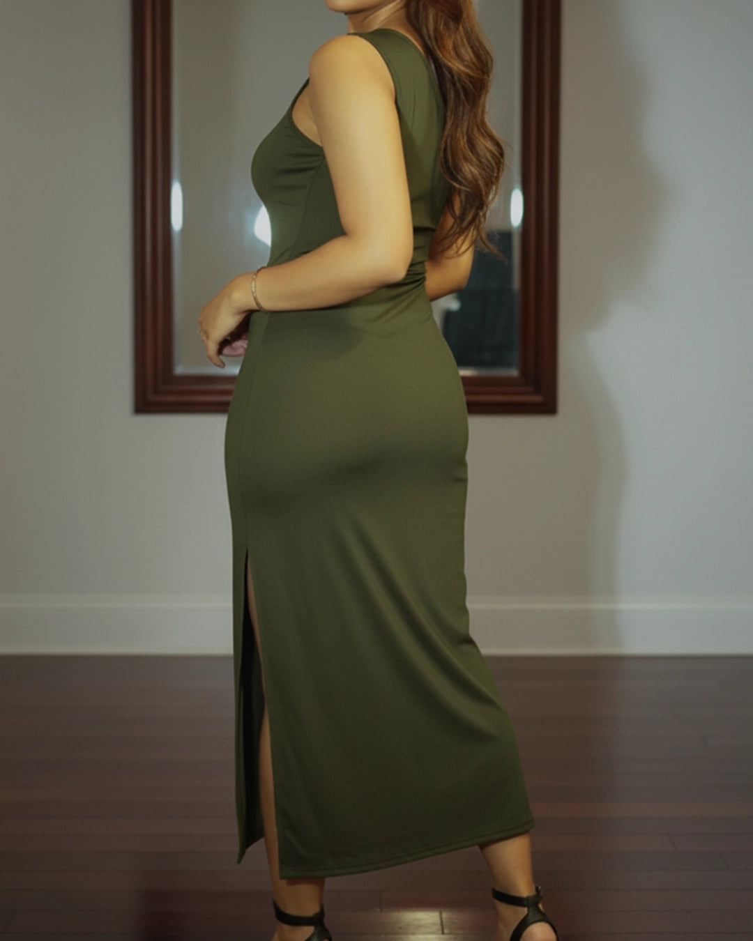 Woman wearing a green dress with a slit, standing in front of a mirror.