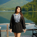 Woman standing on a wooden dock by a lake with mountains in the background