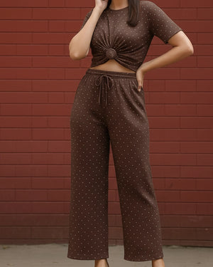 Person wearing a brown polka dot outfit against a red brick wall