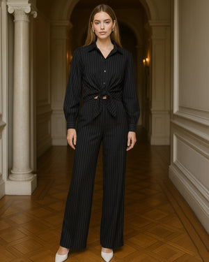 Woman wearing a black pinstripe outfit standing in an elegant hallway.