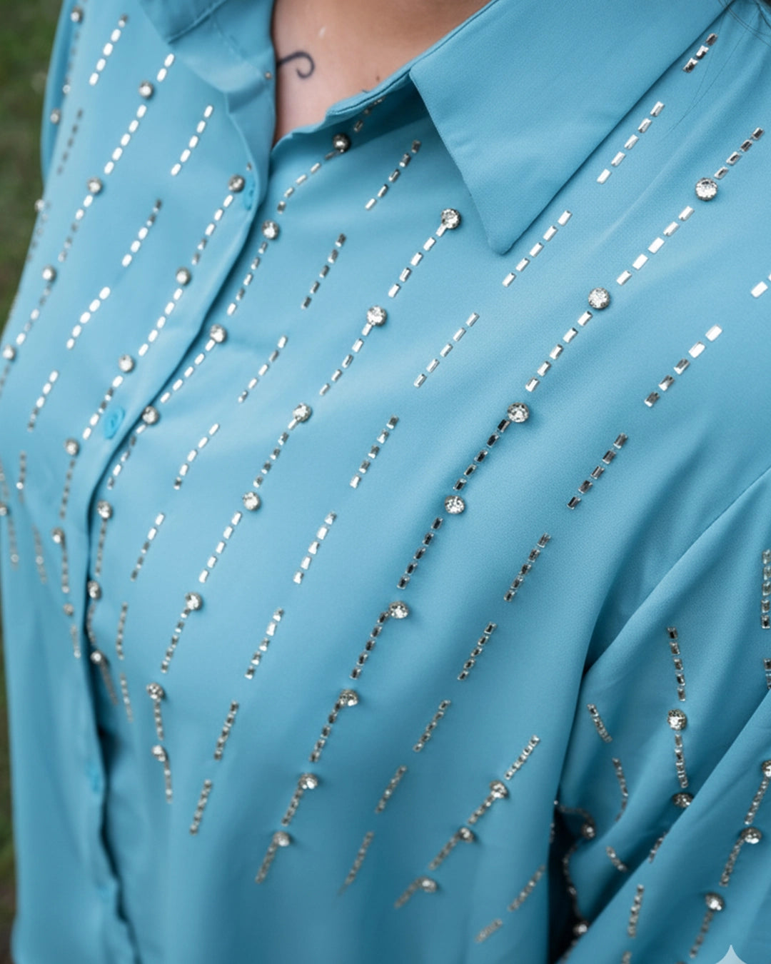 Close-up of a blue shirt with silver bead embellishments.