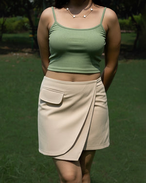 Person wearing a green top and beige skirt outdoors
