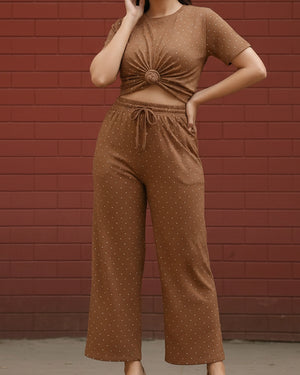 Person wearing a brown polka dot outfit against a red brick wall