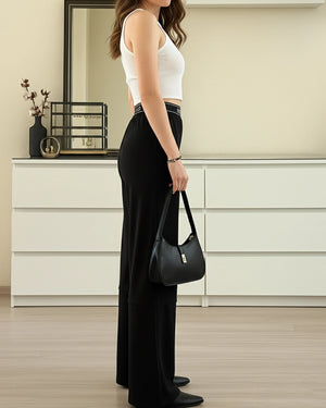Woman holding a black handbag in a room with white cabinets.