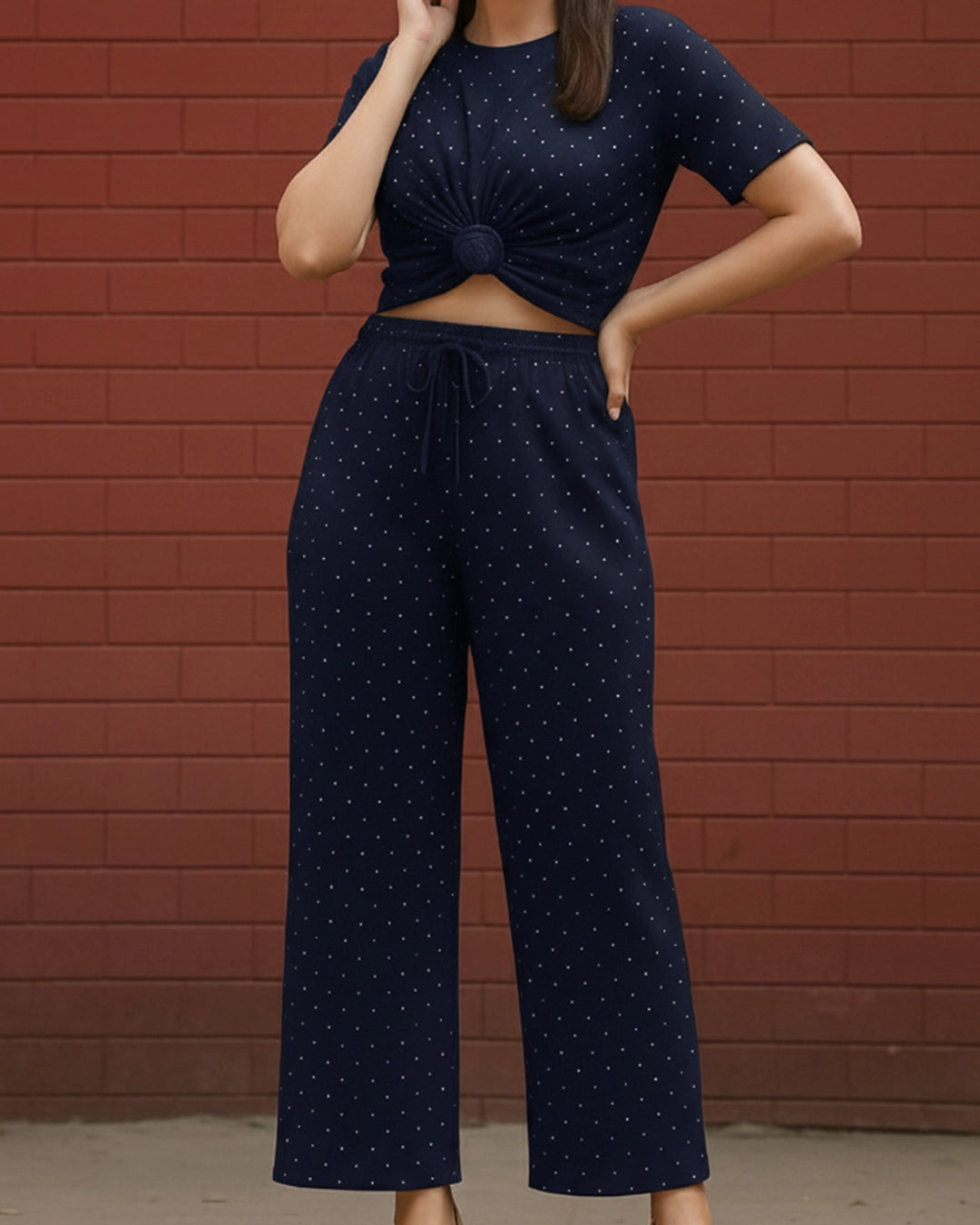 Person wearing a navy blue outfit with white patterns against a red brick wall.