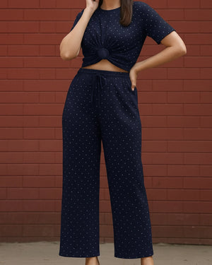Person wearing a navy blue outfit with white patterns against a red brick wall.