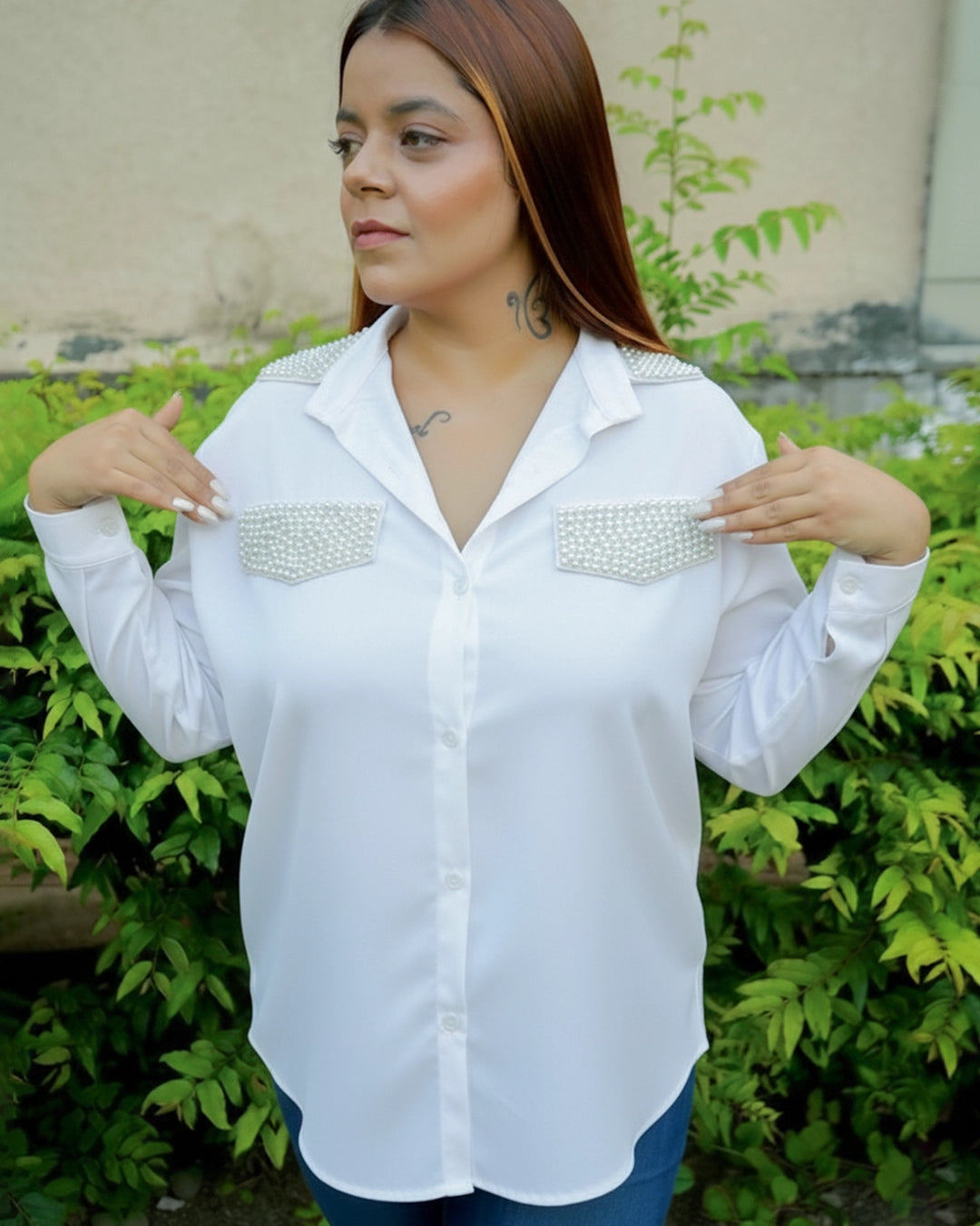 Woman wearing a white blouse with pearl embellishments in an outdoor setting