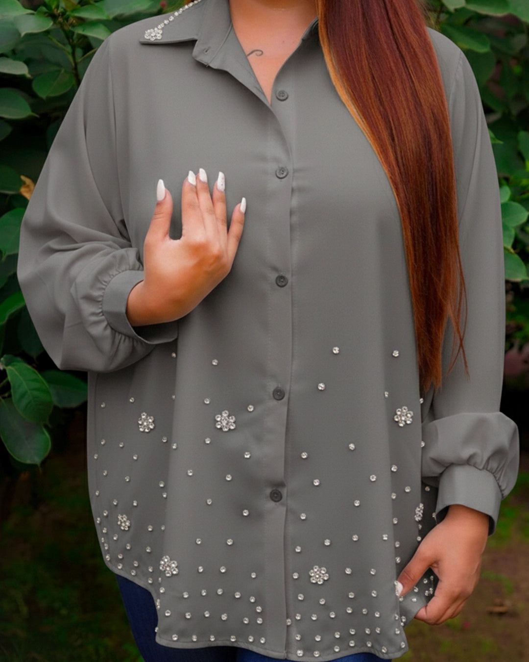 Gray blouse with floral embellishments worn by a person outdoors.
