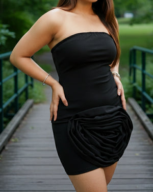 Woman wearing a black strapless dress with a ruched skirt on a wooden bridge.