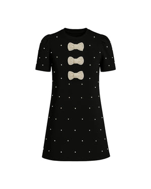 Black dress with white polka dots and beige bows on a white background