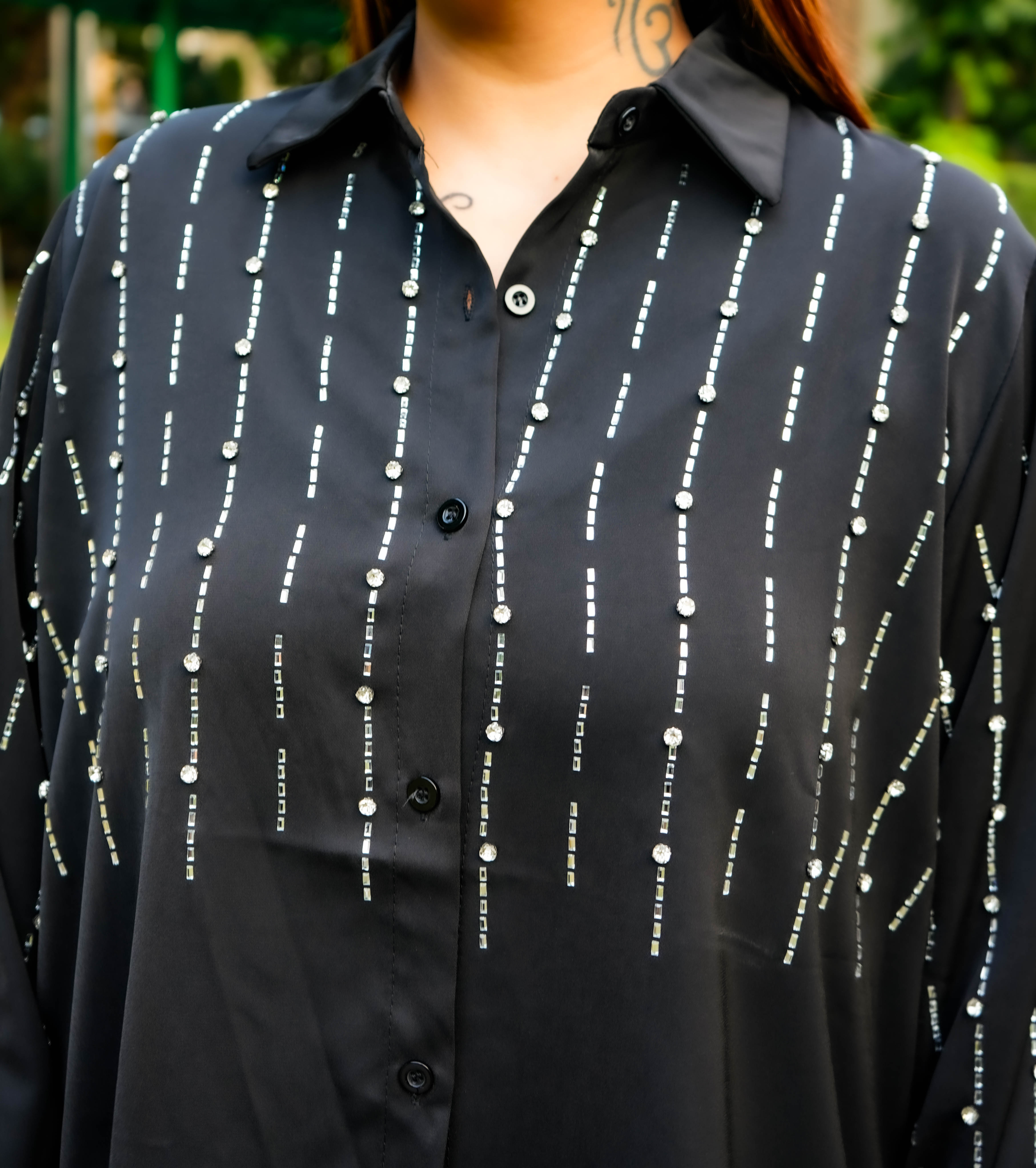 Black shirt with white pattern worn by a person, blurred background