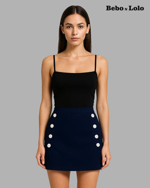 Woman wearing a black top and navy skirt with white buttons on a gray background, branded 'Bebó n Lolo'.
