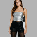 Woman wearing a silver top and black sequin pants on a gray background
