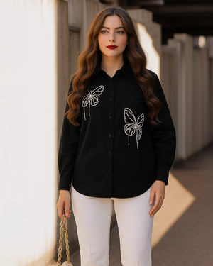 Woman wearing a black shirt with butterfly designs outdoors